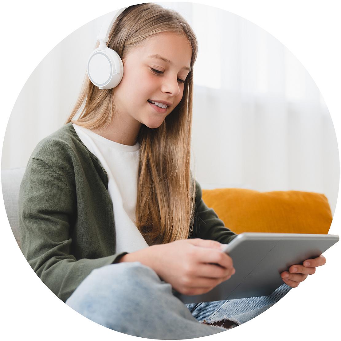 Junge Schülerin mit Kopfhörern am Tablet