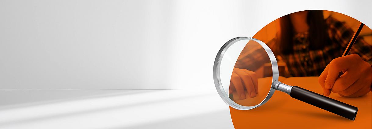 Lupe, schreibende Hand im Hintergrund